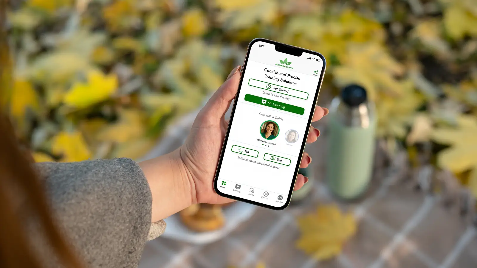 Guiding Growth mobile app shown on a phone held in an assisted living employee's hand